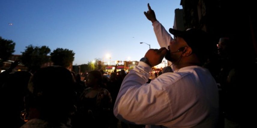 Pastor Gabriel Churn of West Baltimore's Union Temple Congregation leads his congregation in a prayer for peace in their neighborhood during a sunset prayer service on the sidewalk in front of their church near the scene of recent rioting over the death of 25-year-old Freddie Gray while in police custody in Baltimore, Maryland April 28, 2015.  REUTERS/Jim Bourg - RTX1AQKC